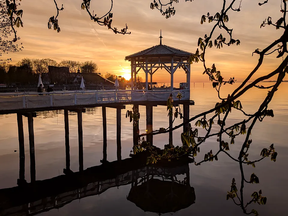 Pavillon am Seeufer in Bregenz bei Sonnenuntergang, gespiegelt im Wasser